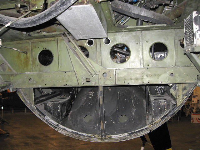 TBM_42.jpg - Forward bomb/torpedo compartment. On either side would be to batteries sitting on the black platforms. Through two holes is the oil cooler flap which is opened to aid flow of air when plane is idling. Above is attachment point for the lever system that opens and closes bom bay.